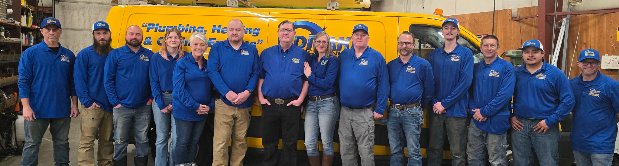 The Drake Mechanical team in blue uniforms in front of a yellow service van